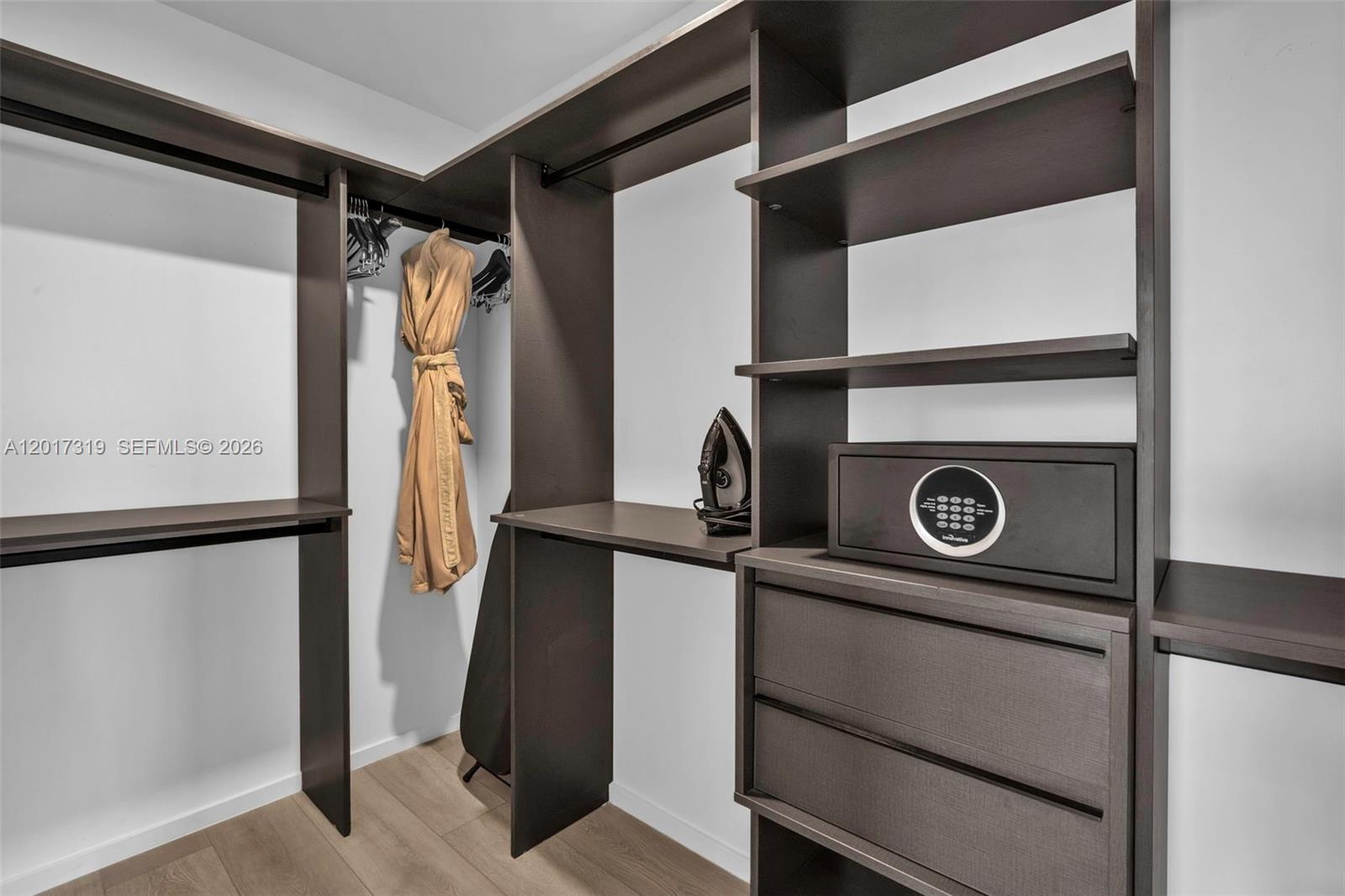 A walk-in closet features dark wood shelving, a built-in safe, and a hanging robe — 398 NE 5th St # 4701, Miami FL 33132, MIAMI, FL