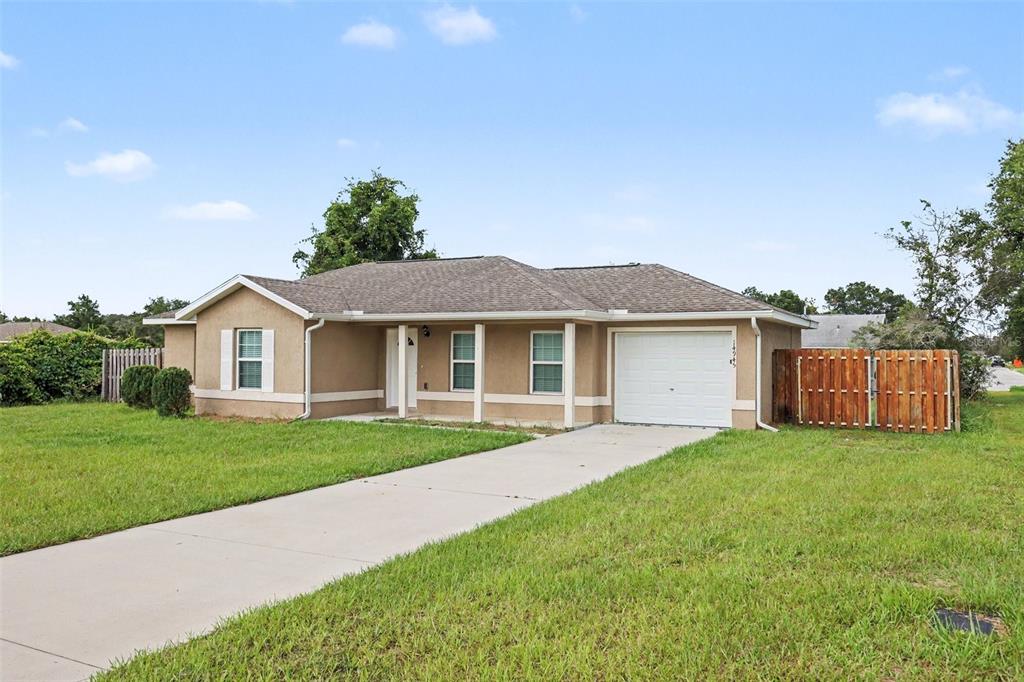 A single-story tan house with a white garage door and a concrete driveway — 14945 SW 39TH CIRCLE, OCALA, FL