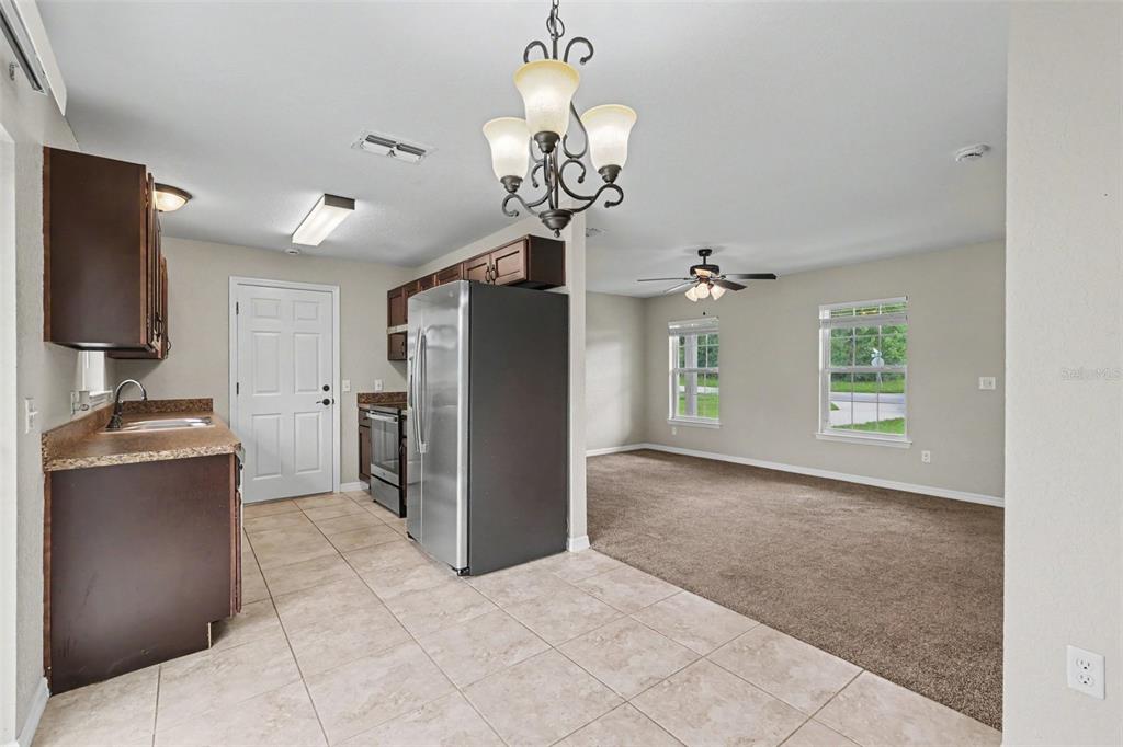 A kitchen with tile floors and stainless steel appliances opens into a carpeted living area — 14945 SW 39TH CIRCLE, OCALA, FL