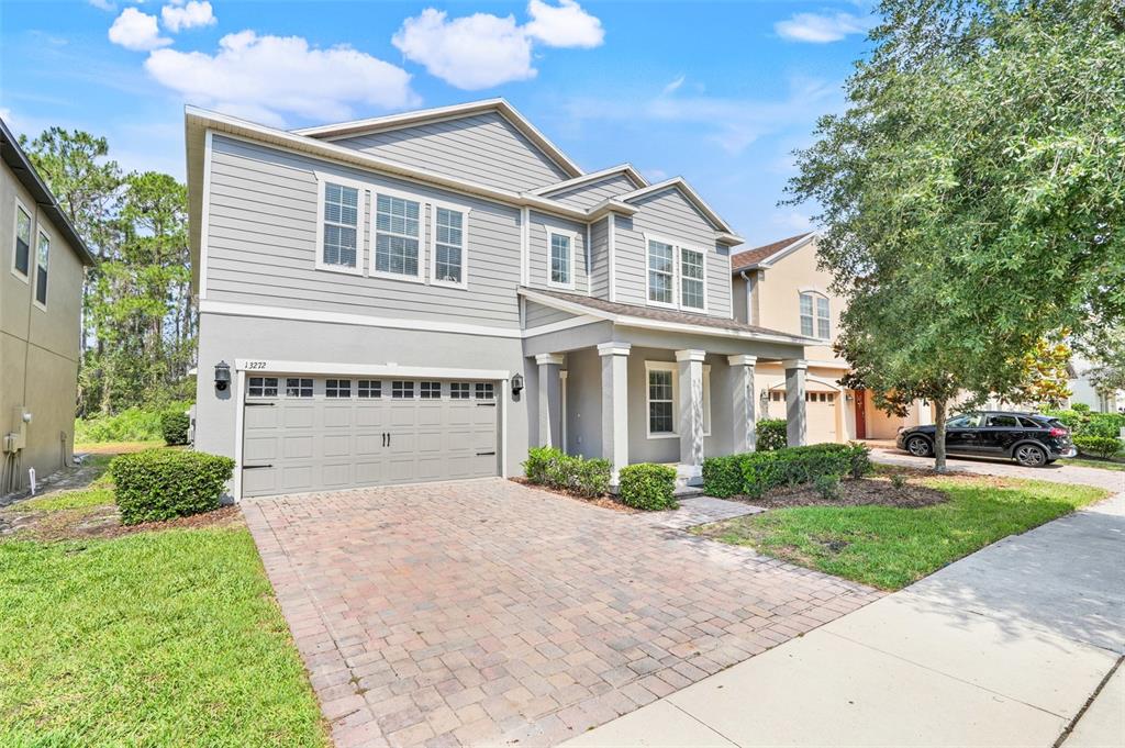 A two-story gray house with a brick driveway and a two-car garage — 13272 PENSHURST LANE, WINDERMERE, FL