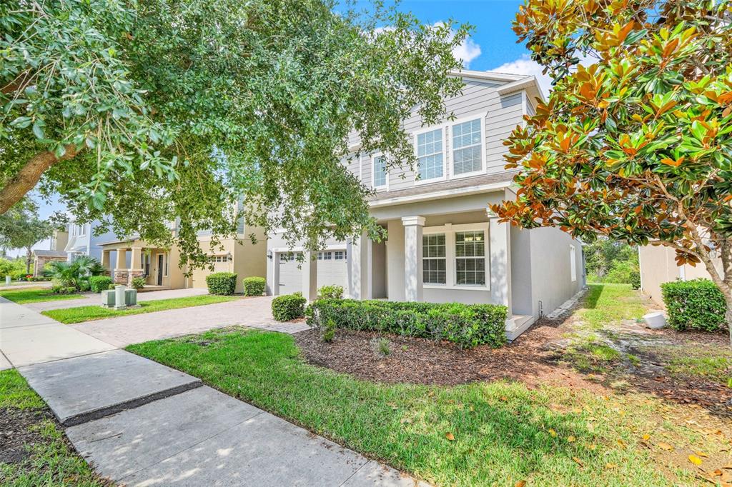 A two-story house with gray siding, a paved driveway, and a landscaped front yard — 13272 PENSHURST LANE, WINDERMERE, FL