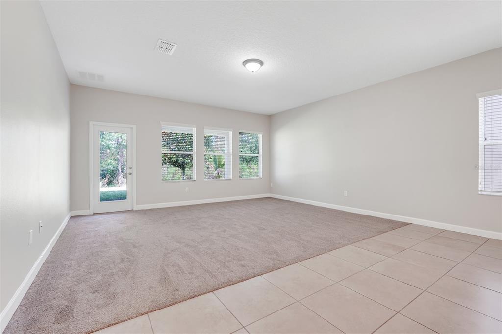 A living room features beige walls, a carpeted area, tiled flooring, and a glass door — 13272 PENSHURST LANE, WINDERMERE, FL