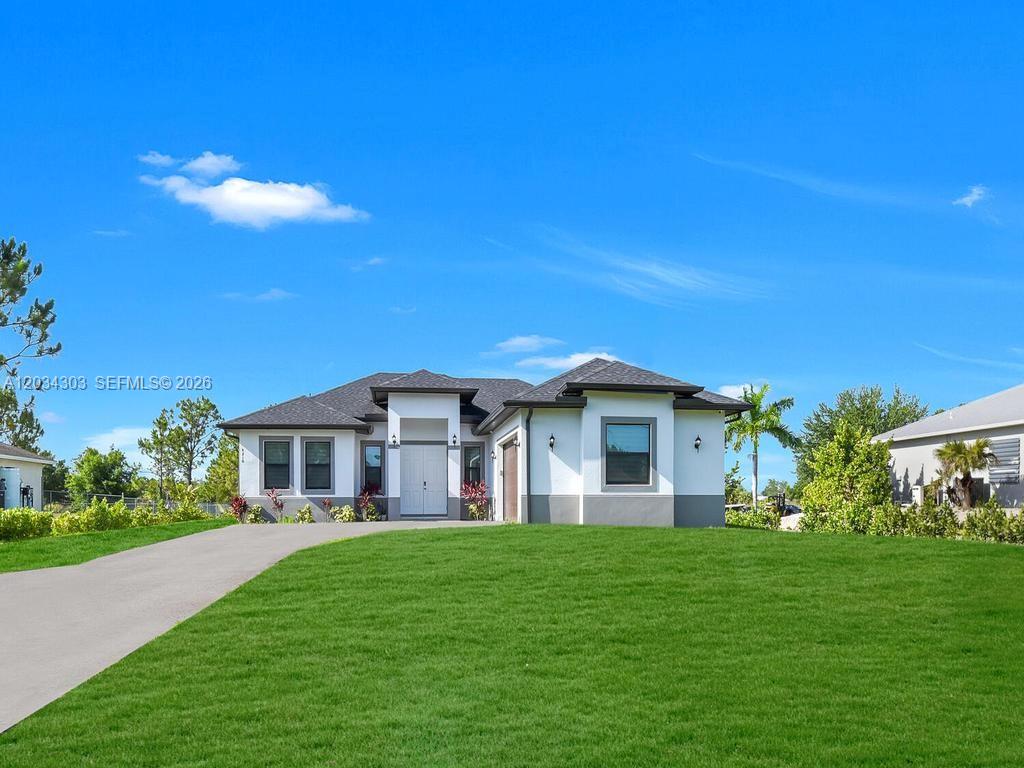 A single-story house with a white stucco exterior, dark roof, and a front lawn — 4210 58th Ave NE, Naples FL 34120, NAPLES, FL