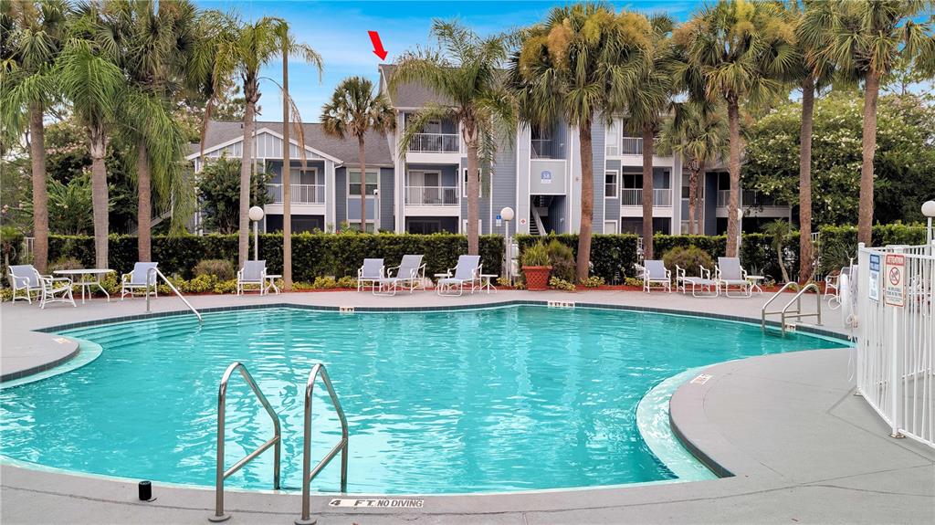 A swimming pool sits in front of a multi-story apartment building with palm trees — 2516 GRASSY POINT DRIVE UNIT 306, LAKE MARY, FL