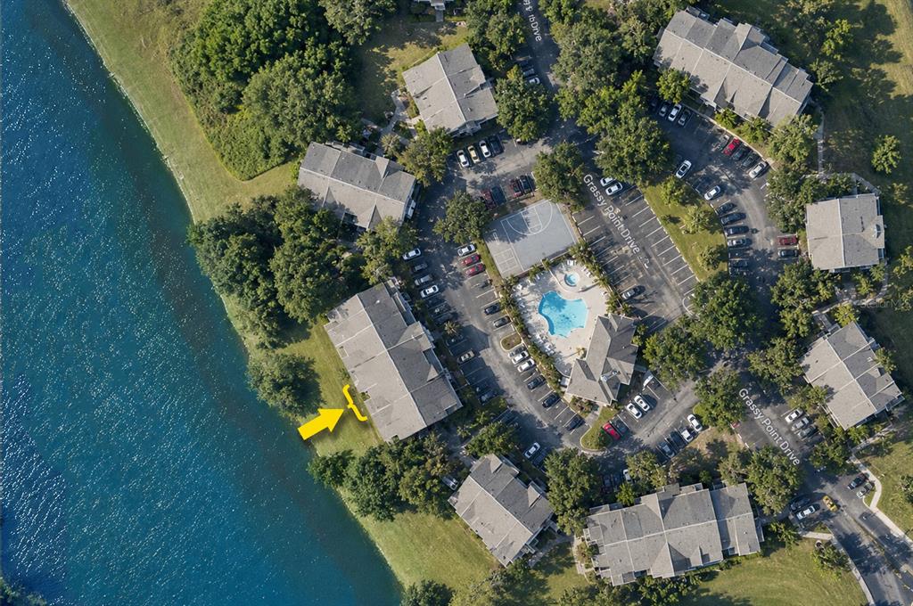 An aerial view shows a multi-unit residential building situated next to a lake — 2516 GRASSY POINT DRIVE UNIT 306, LAKE MARY, FL