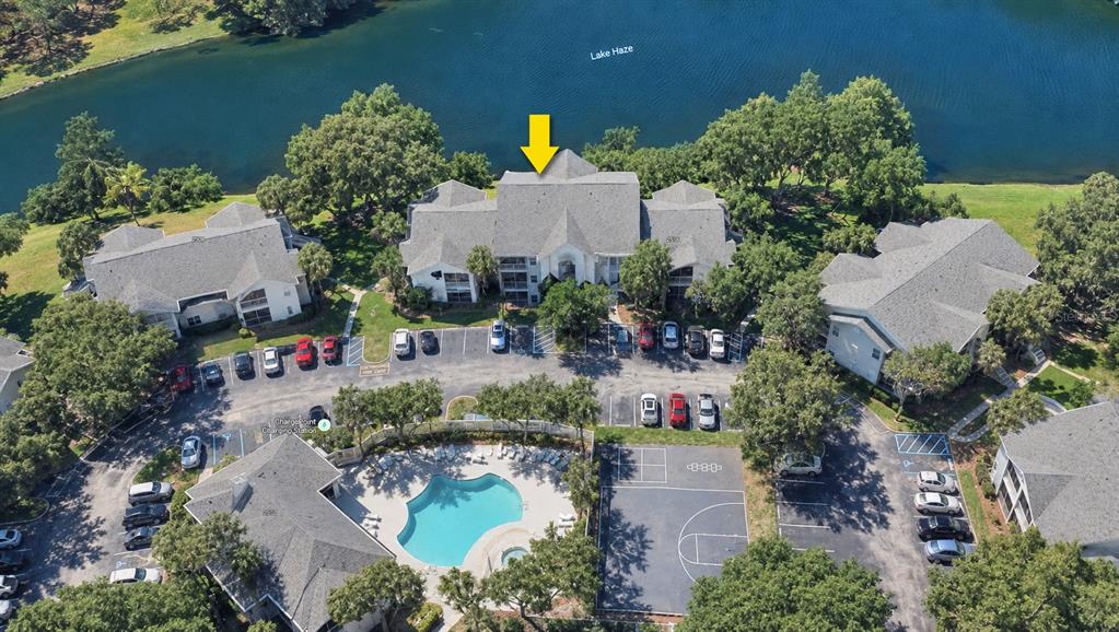 An aerial view shows a multi-story apartment building with a pool and basketball court nearby — 2516 GRASSY POINT DRIVE UNIT 306, LAKE MARY, FL