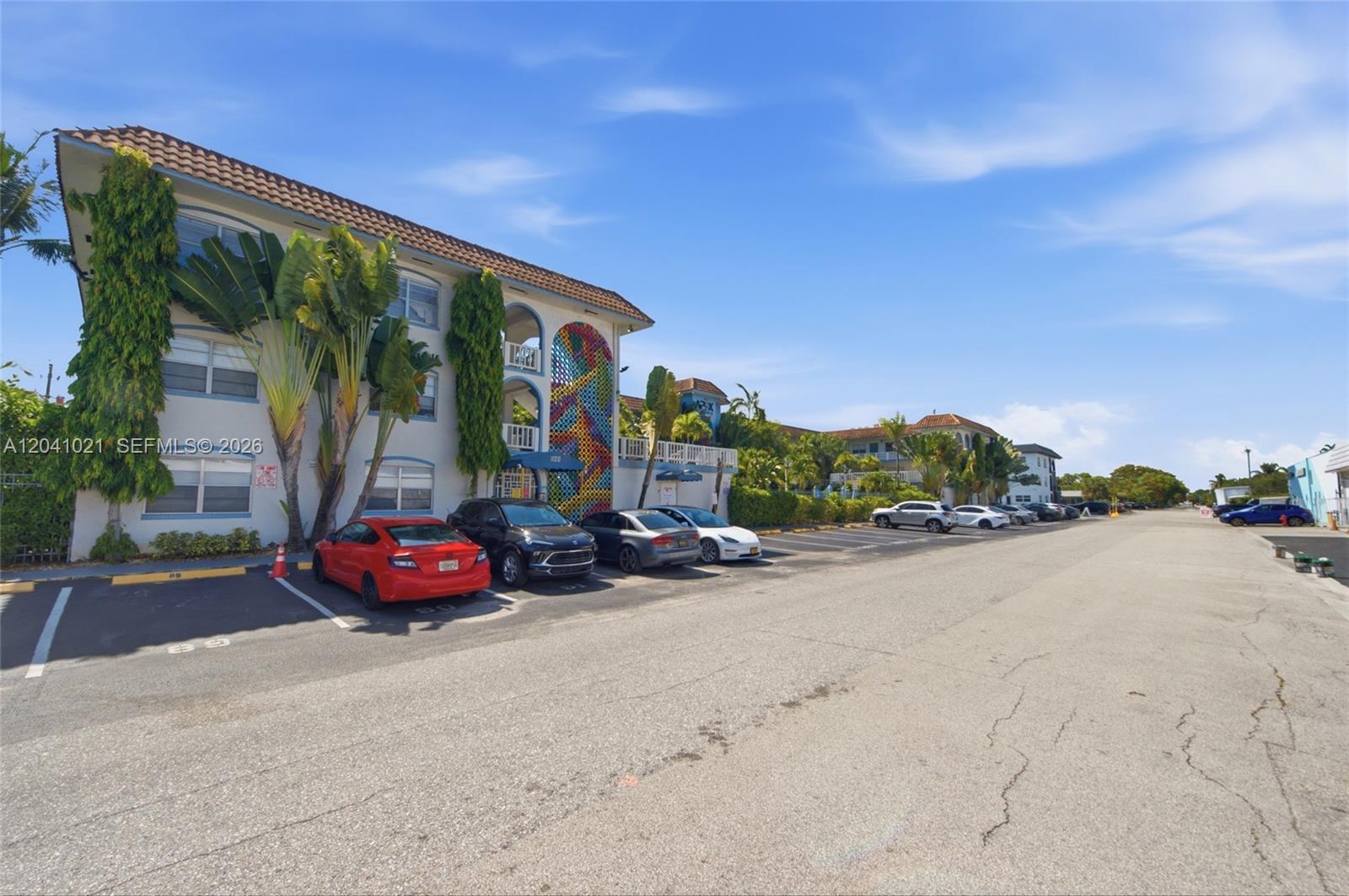 A multi-story apartment building with a colorful mural stands beside a parking lot — FORT LAUDERDALE, FL