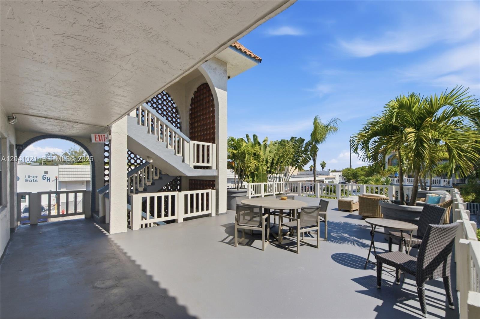 An outdoor patio features a dining set, lounge chairs, and a staircase under a roof — FORT LAUDERDALE, FL
