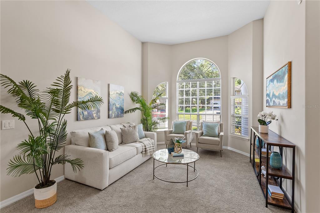 A living room features a beige sofa, two armchairs, a glass coffee table, and tall windows — 690 OAK HOLLOW WAY, ALTAMONTE SPRINGS, FL