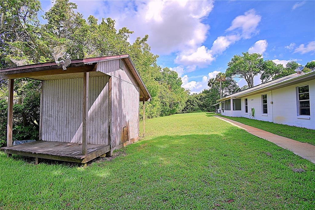 A wooden shed stands on a grassy lawn next to a white house exterior — 3289 S NOVA ROAD, PORT ORANGE, FL