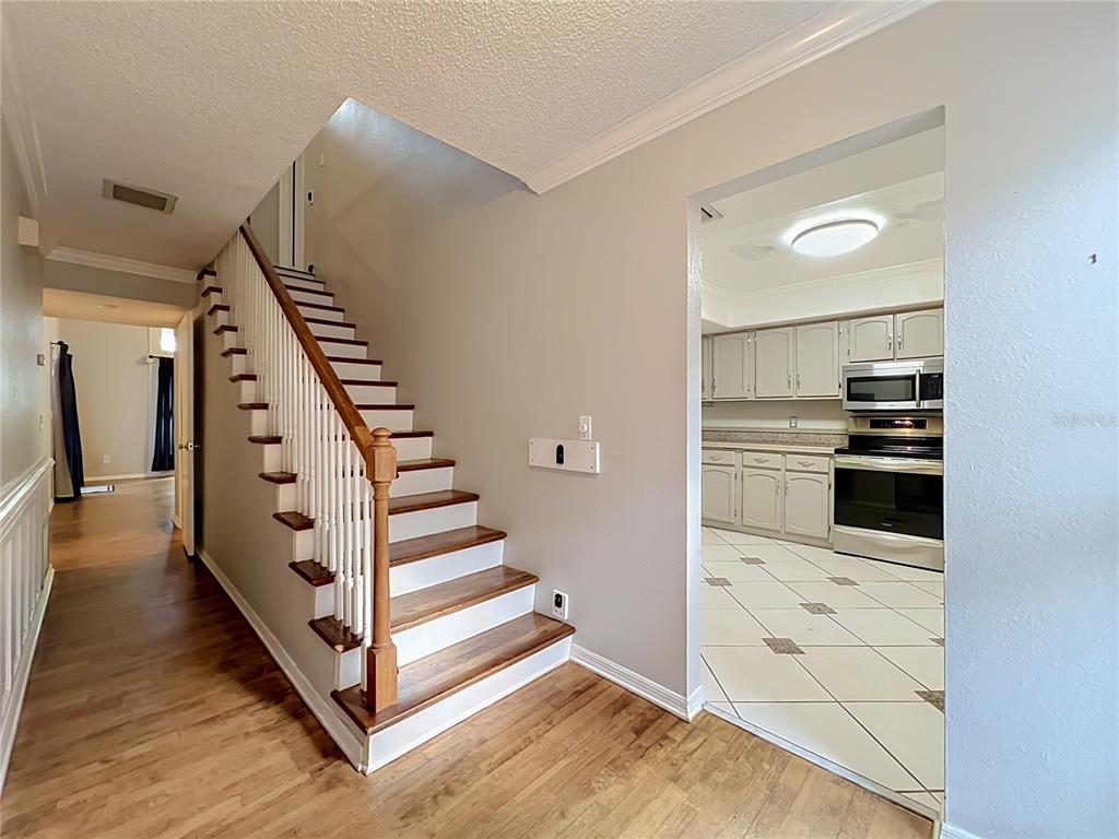 A staircase with wooden treads and white railings stands beside a kitchen with tiled floors — 814 LAUREL AVENUE UNIT 2, ORLANDO, FL