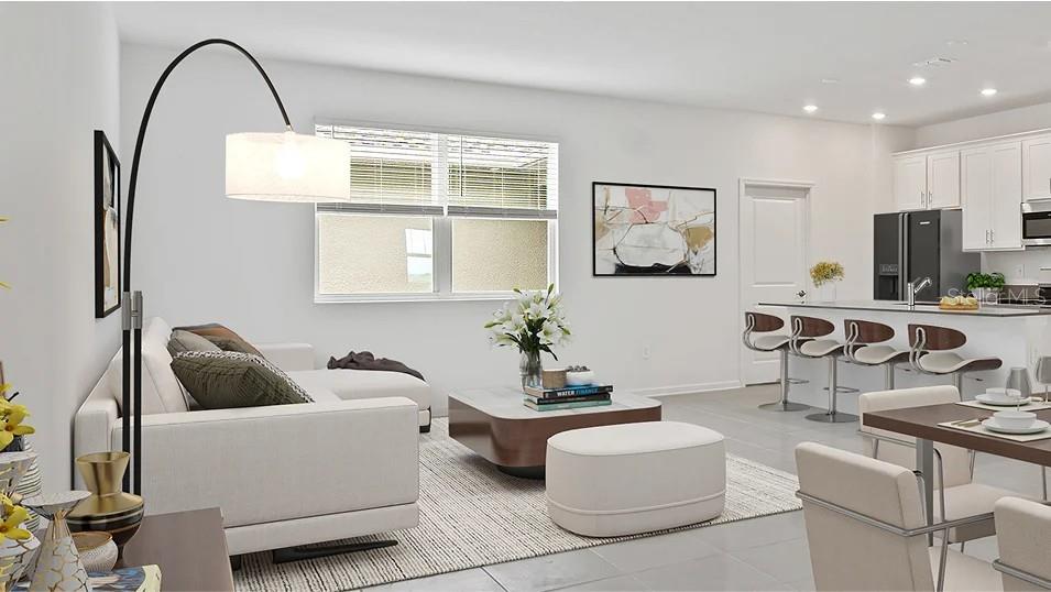 This open-concept living area features a white sofa, a modern coffee table, and a kitchen — 5543 RONIN DRIVE, ST CLOUD, FL