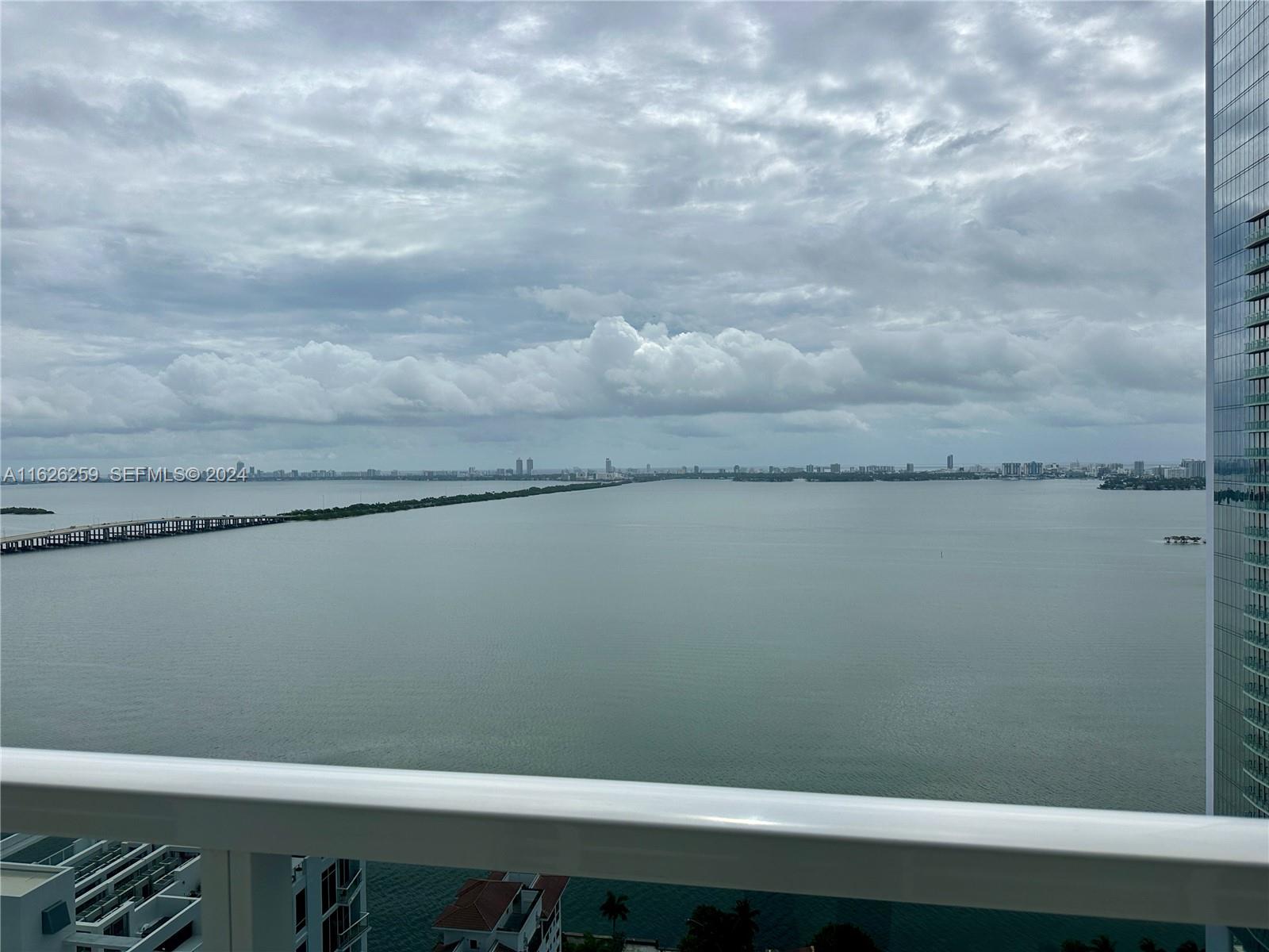 A balcony view overlooks a large bay with a long bridge and distant city skyline — 600 NE 27th St # 2302, Miami FL 33137, MIAMI, FL