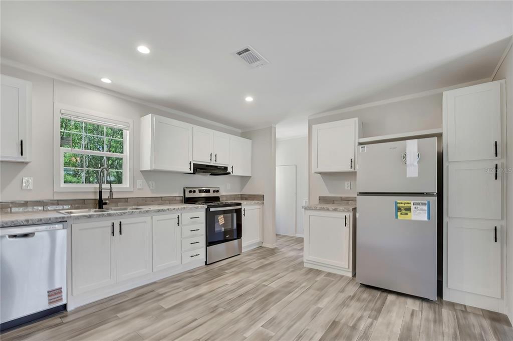 A kitchen features white cabinets, stainless steel appliances, and light-colored wood-look flooring — 4540 N WINCHESTER TERRACE, HERNANDO, FL