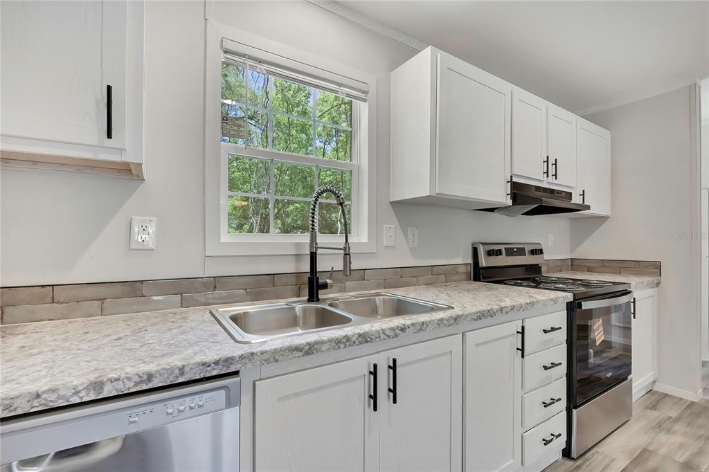 A kitchen with white cabinets, stone-look countertops, a stainless steel sink, and stainless appliances — 4540 N WINCHESTER TERRACE, HERNANDO, FL