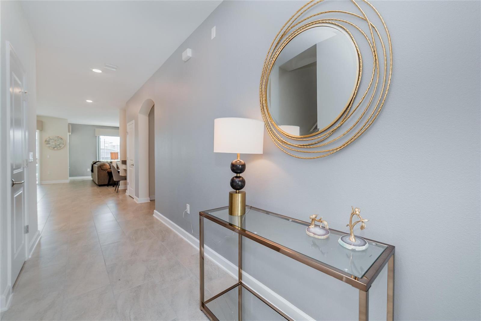 A hallway features a glass console table, a modern lamp, and a decorative gold mirror — 8936 Cabot Cliffs, Davenport FL 33896, DAVENPORT, FL