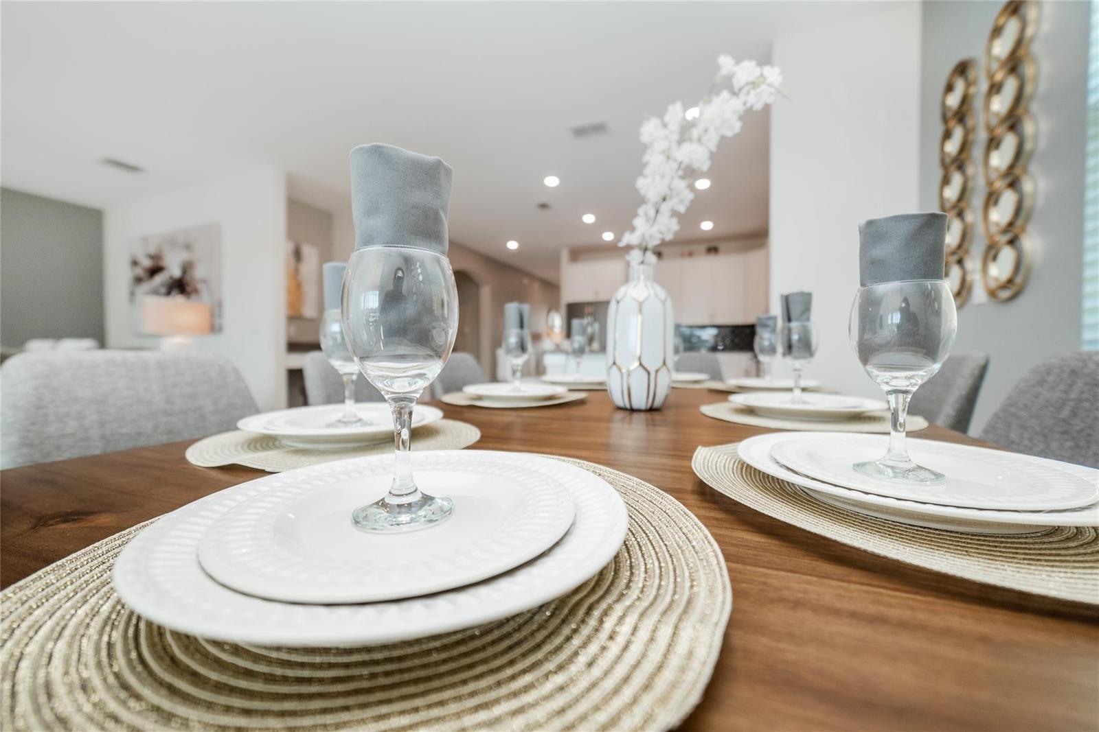 A dining table is set with white plates, wine glasses, and gray napkins — 8936 Cabot Cliffs, Davenport FL 33896, DAVENPORT, FL
