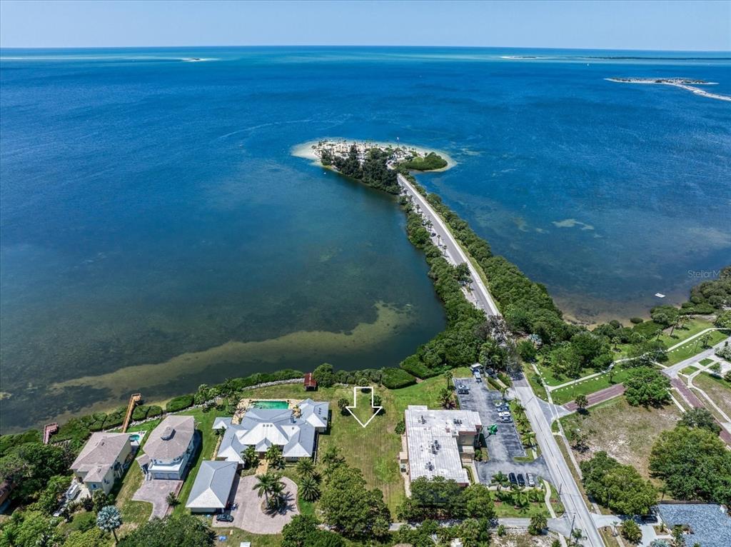 An aerial view shows a waterfront property with a vacant lot and nearby buildings — 1725 GULF ROAD, TARPON SPRINGS, FL
