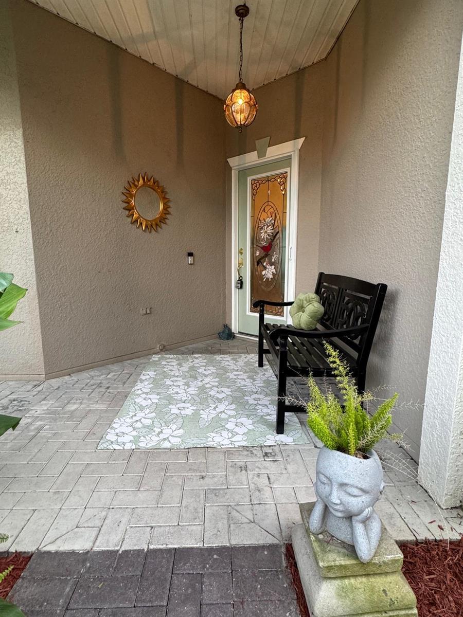 A covered front porch features a light green door, a black bench, and a patterned rug — 176 Cape Florida Drive, FL 34759, FL