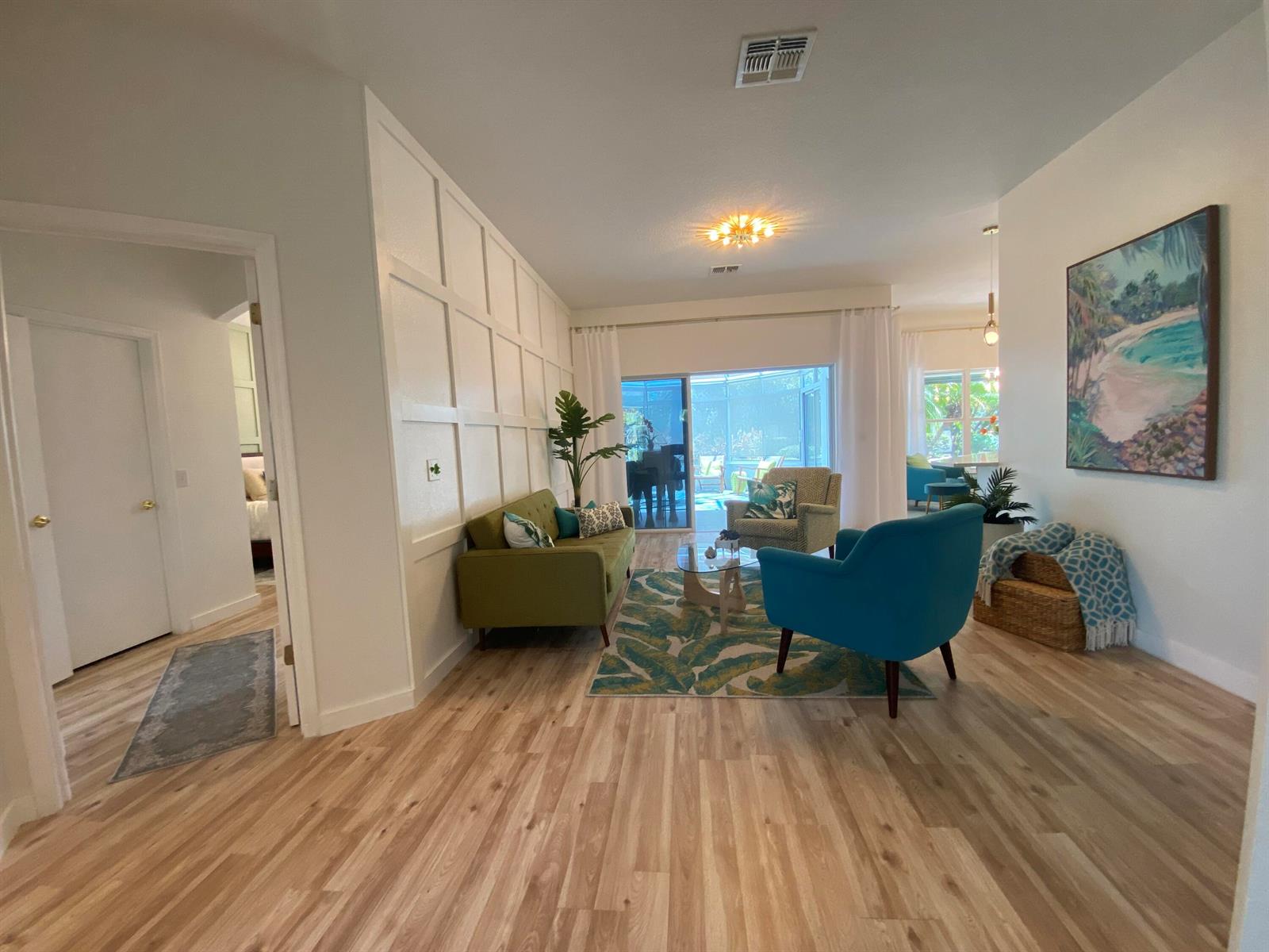A living room features a green sofa, blue armchair, patterned rug, and white grid wall — 176 Cape Florida Drive, FL 34759, FL