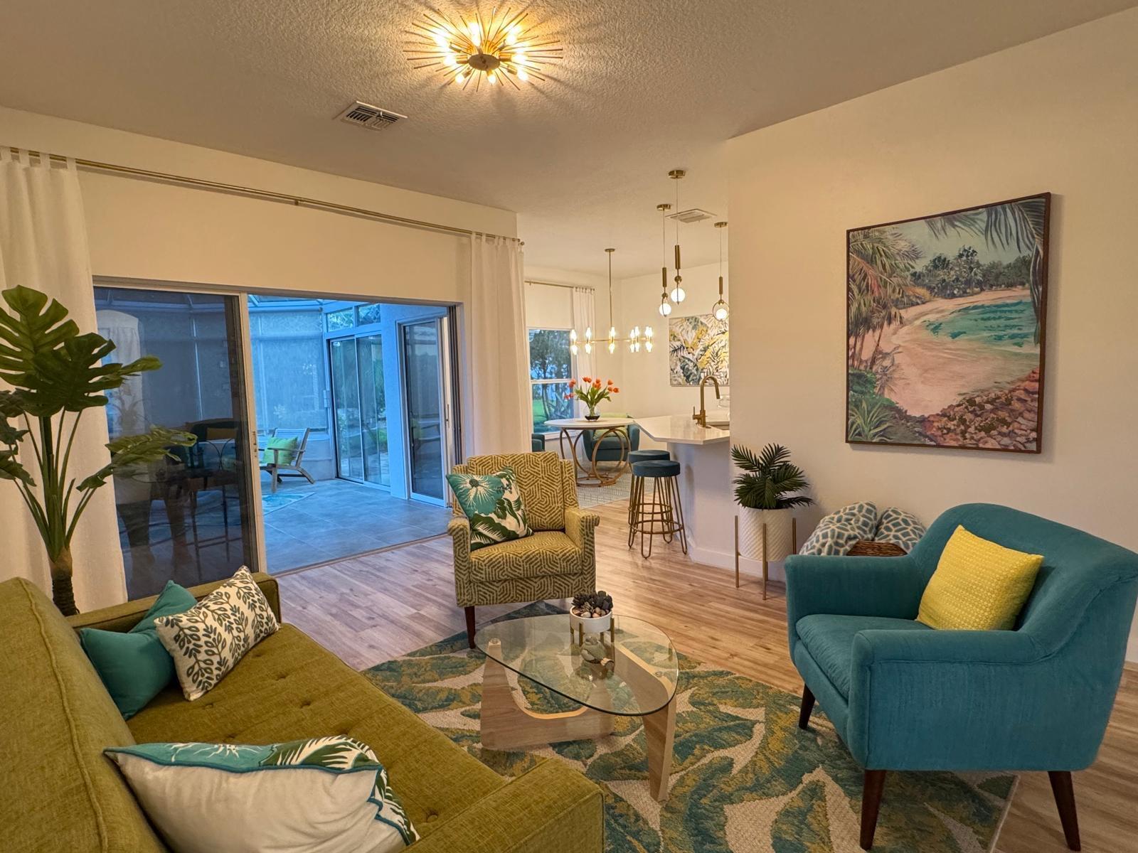 A living room features a green sofa, teal armchair, patterned rug, and a sliding glass door — 176 Cape Florida Drive, FL 34759, FL