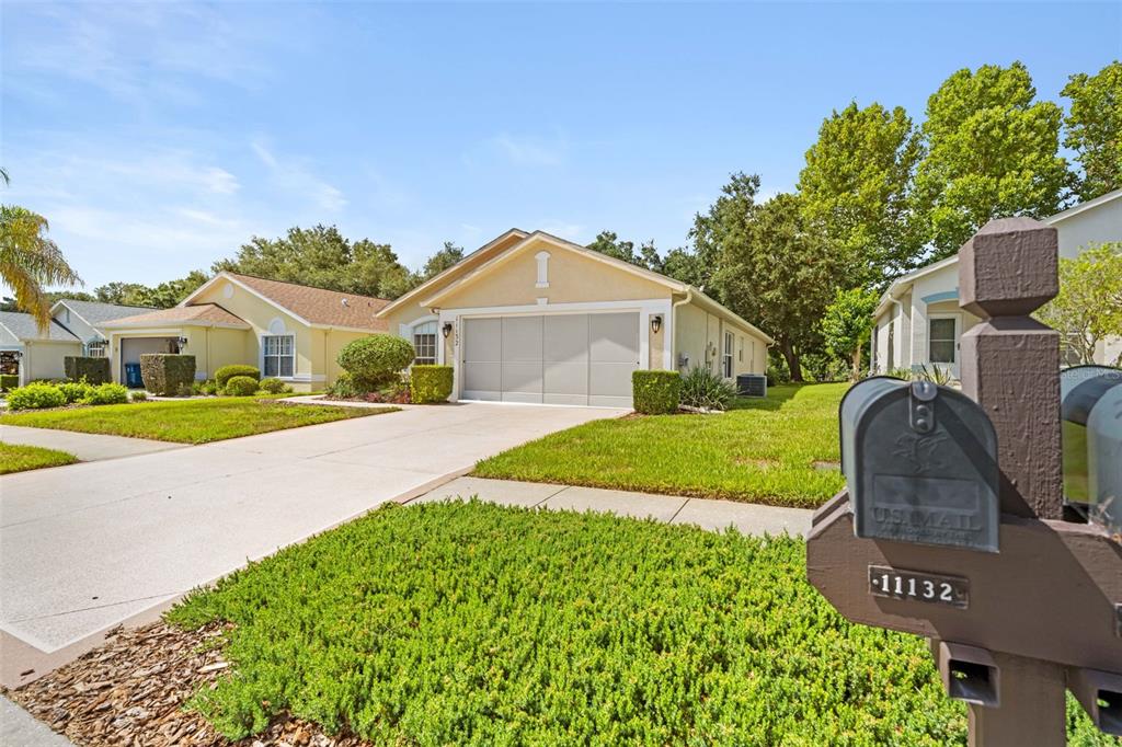 A suburban house with a beige stucco exterior, a two-car garage, and a front lawn — 11132 HEATHROW AVENUE, SPRING HILL, FL