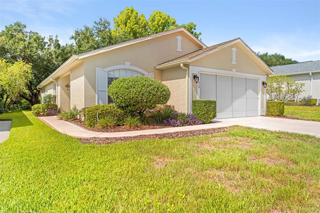 A single-story house with a beige stucco exterior, a two-car garage, and landscaped front yard — 11132 HEATHROW AVENUE, SPRING HILL, FL