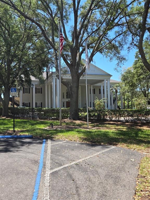 A two-story white building with a columned portico stands behind a parking lot — 5712 SUMMERBROOKE COURT, LEESBURG, FL