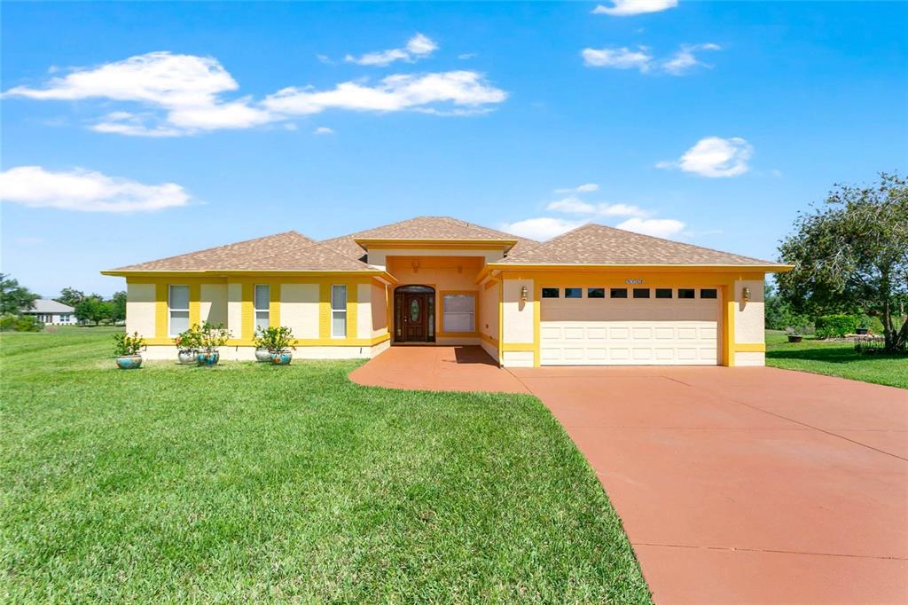 A single-story house with a tan stucco exterior, yellow trim, and a two-car garage — 5712 SUMMERBROOKE COURT, LEESBURG, FL
