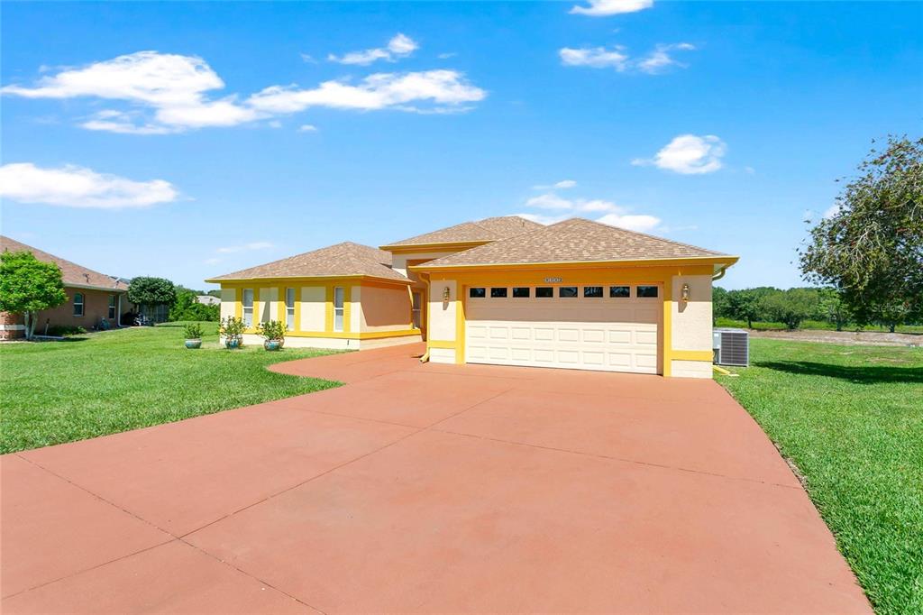A single-story house with a yellow exterior, a two-car garage, and a red driveway — 5712 SUMMERBROOKE COURT, LEESBURG, FL