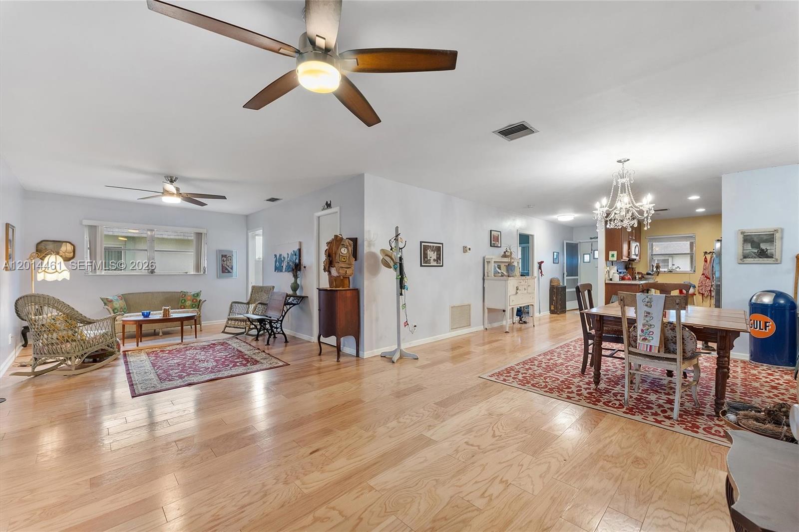 An open-concept living and dining area features hardwood floors, ceiling fans, and a crystal chandelier — 2638 E Gately Dr E # 85, West Palm Beach FL 33415, WEST PALM BEACH, FL