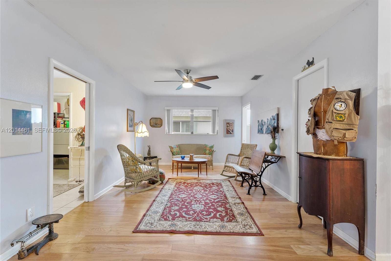 A living room features light-colored walls, wood flooring, a red area rug, and wicker furniture — 2638 E Gately Dr E # 85, West Palm Beach FL 33415, WEST PALM BEACH, FL