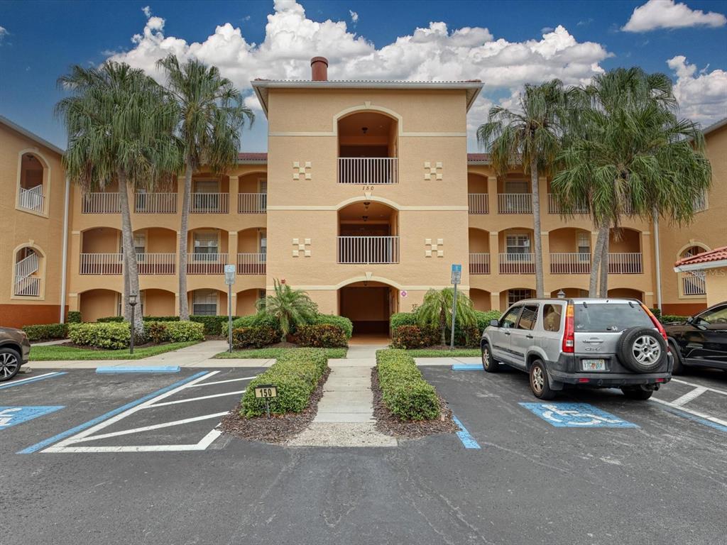 A three-story apartment building with a central entrance and parking spaces in the foreground — 150 L PAVIA BOULEVARD UNIT 13, VENICE, FL