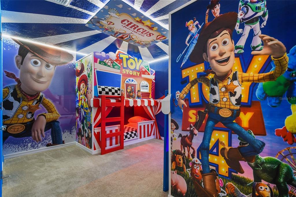 A themed bedroom features Toy Story wall murals, a circus-style bunk bed, and carpeted flooring — 3740 LANA AVENUE, DAVENPORT, FL