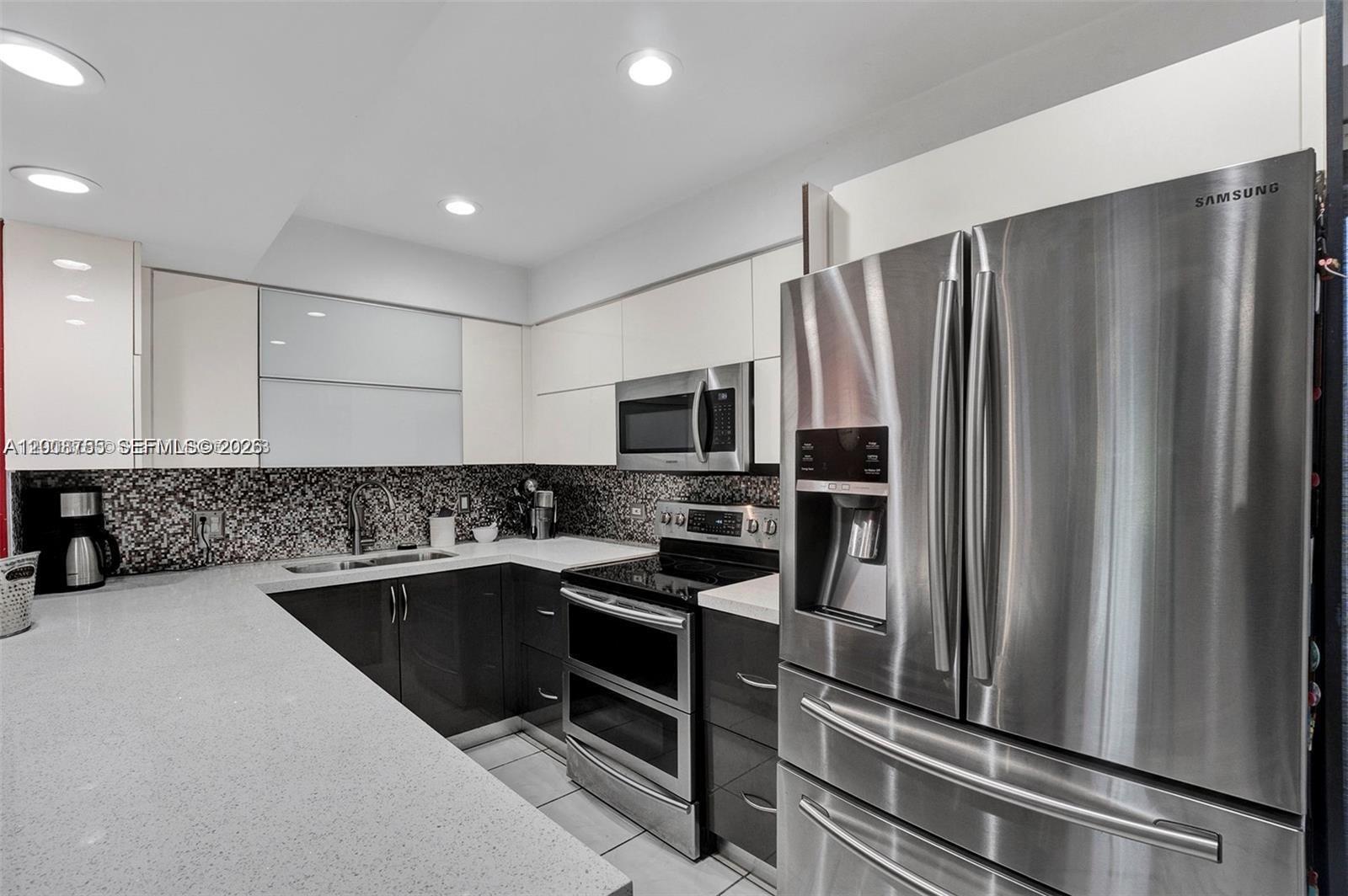 A modern kitchen features stainless steel appliances, dark lower cabinets, and white upper cabinets — 6821 Brookline Dr # 6821, Hialeah FL 33015, HIALEAH, FL