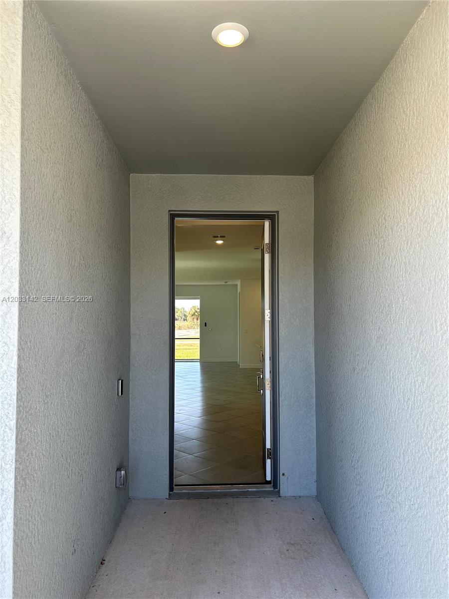 A view through an open doorway into an empty room with tiled flooring — 20483 Copperhead DR, Lehigh Acres FL 33936, LEHIGH ACRES, FL