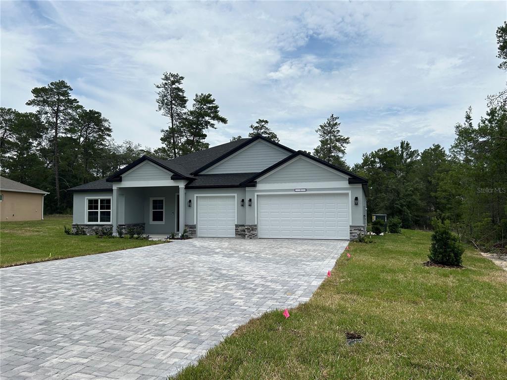 A single-story house with a paved driveway, three-car garage, and light-colored siding — 2040 W TALL OAKS DRIVE, BEVERLY HILLS, FL