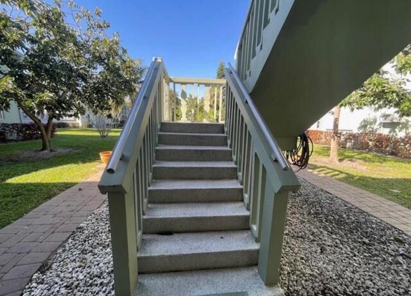 An outdoor concrete staircase with green railings leads to an elevated landing — 66 Easthampton C # C, West Palm Beach FL 33417, WEST PALM BEACH, FL