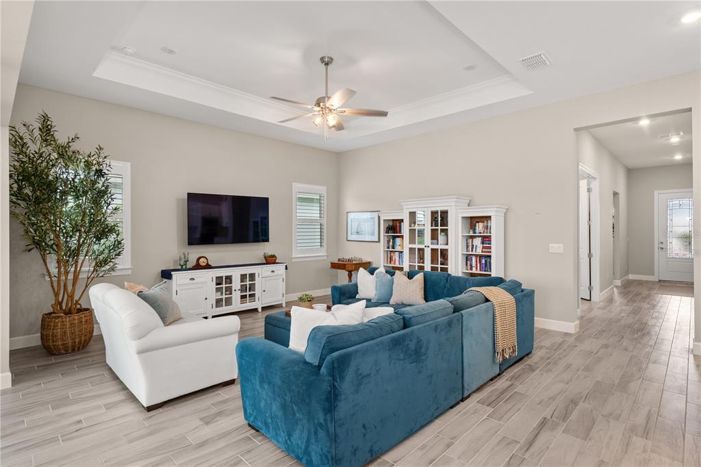 A spacious open-concept living room and kitchen featuring blue sectional seating and light tile flooring — 9982 BRIGHT WATER DRIVE, ENGLEWOOD, FL