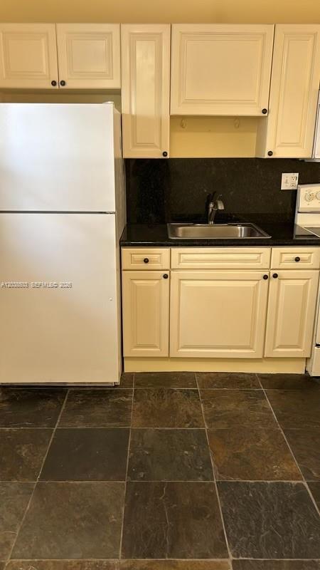A kitchen features white cabinetry, a white refrigerator, a dark countertop, and slate tile flooring — 1600 NE 114th St # 208, Miami FL 33181, MIAMI, FL