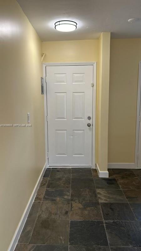 An entryway features a white door, light yellow walls, and dark slate tile flooring — 1600 NE 114th St # 208, Miami FL 33181, MIAMI, FL