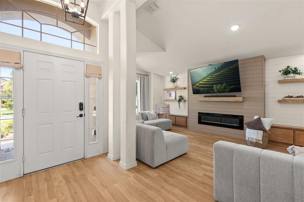 A bright living room features light wood flooring, a fireplace with a television, and furniture — 4071 LONGWORTH LOOP, KISSIMMEE, FL