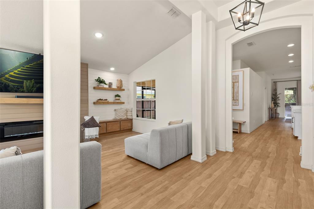 A living room features light wood flooring, a fireplace, floating shelves, and a vaulted ceiling — 4071 LONGWORTH LOOP, KISSIMMEE, FL