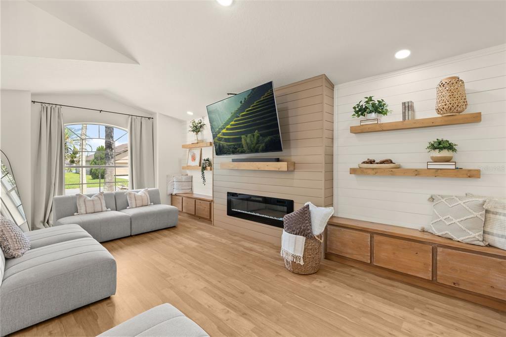A living room features a fireplace with a mounted television, wood shelving, and light flooring — 4071 LONGWORTH LOOP, KISSIMMEE, FL