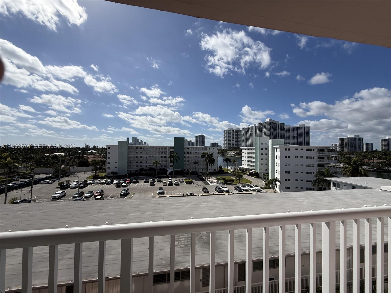 A balcony view overlooks a parking lot, residential buildings, and a canal under a cloudy sky — 3161 S Ocean Dr # 608, Hallandale Beach FL 33009, HALLANDALE BEACH, FL