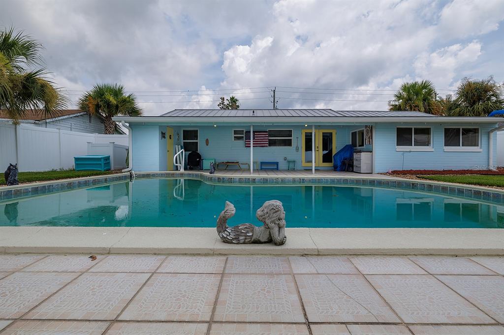 A light blue house with a metal roof overlooks a backyard swimming pool and patio — 270 BOYLSTON AVENUE, DAYTONA BEACH, FL