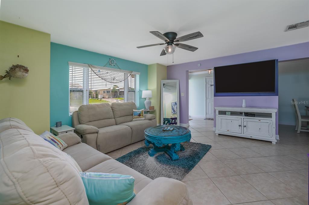 A living room features a beige sofa, a blue coffee table, and colorful accent walls — 270 BOYLSTON AVENUE, DAYTONA BEACH, FL