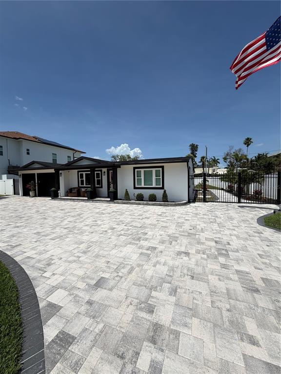 A white single-story house features a large paver driveway and a black metal fence — 3921 BELLE VISTA DRIVE E, ST PETE BEACH, FL