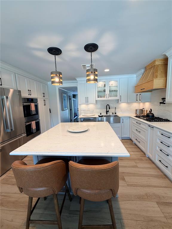 A kitchen features a large white island, stainless steel appliances, and light wood-look flooring — 3921 BELLE VISTA DRIVE E, ST PETE BEACH, FL