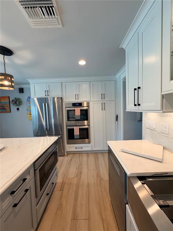 A kitchen features white cabinets, stainless steel appliances, and a marble-topped island — 3921 BELLE VISTA DRIVE E, ST PETE BEACH, FL